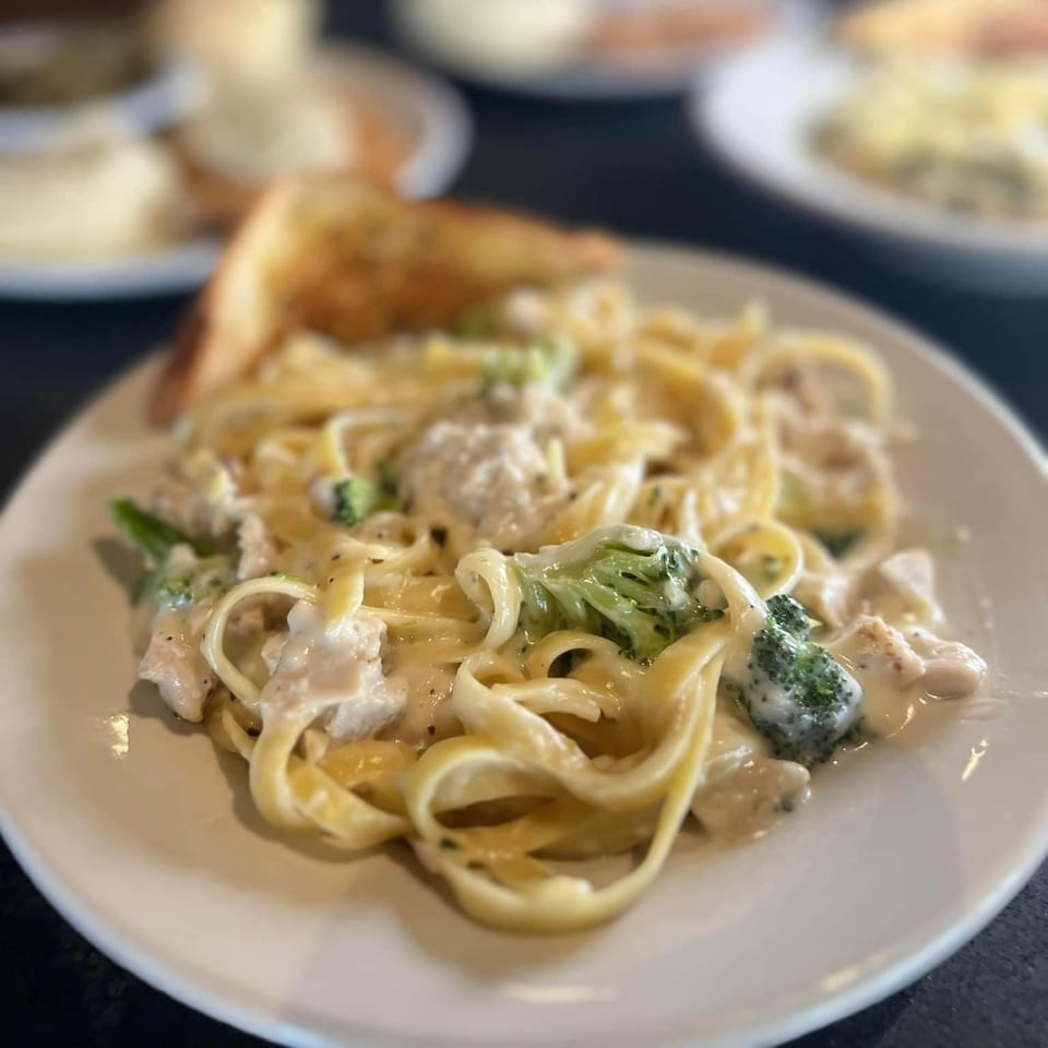 Creamy fettuccine Alfredo with chicken and broccoli, served with garlic bread at Roca Bar.